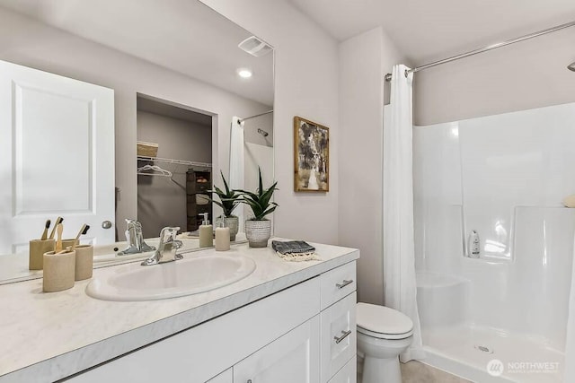 bathroom featuring visible vents, a shower stall, toilet, and vanity