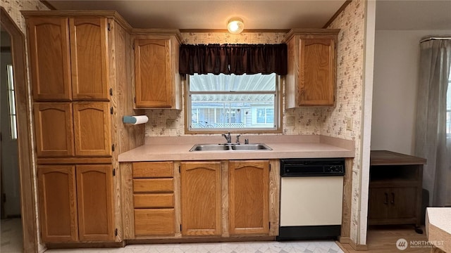 kitchen with dishwasher, wallpapered walls, light countertops, and a sink