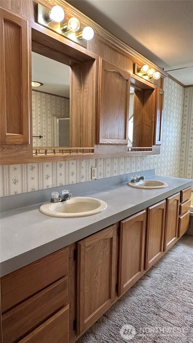 bathroom with a sink, double vanity, and wallpapered walls