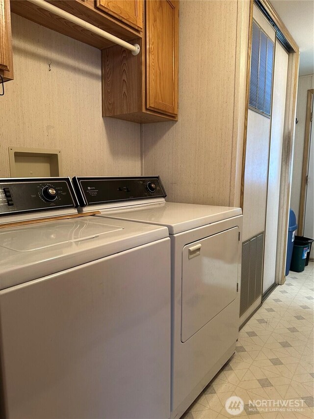 laundry area featuring cabinet space, light floors, and separate washer and dryer