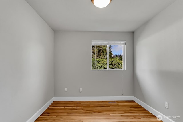 spare room with baseboards and light wood-style floors