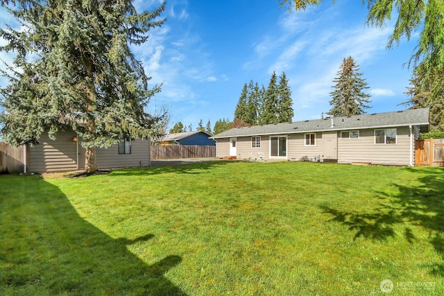 back of house with an outbuilding, a lawn, and a fenced backyard