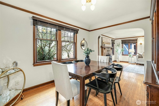 dining room with arched walkways, light wood finished floors, and ornamental molding