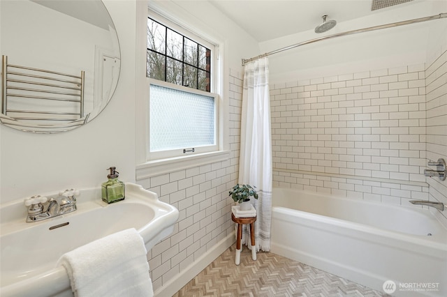 bathroom with a sink, shower / bath combo with shower curtain, and tile walls