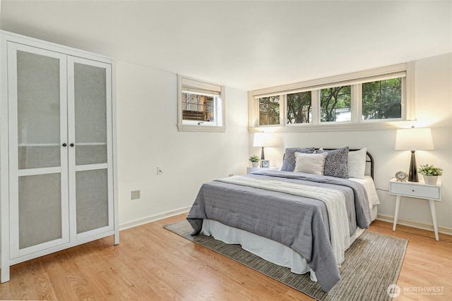 bedroom with french doors, light wood-type flooring, and baseboards