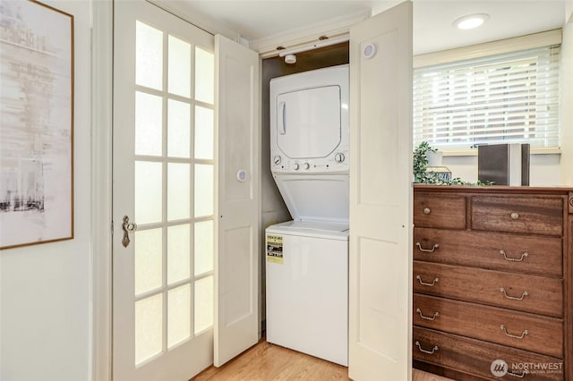 laundry area featuring laundry area, light wood-type flooring, and stacked washing maching and dryer