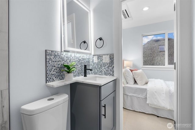 ensuite bathroom featuring vanity, visible vents, ensuite bath, toilet, and tasteful backsplash