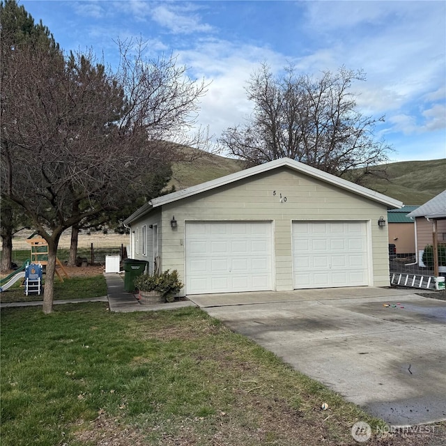 view of side of home featuring a yard, a detached garage, an outdoor structure, and a playground