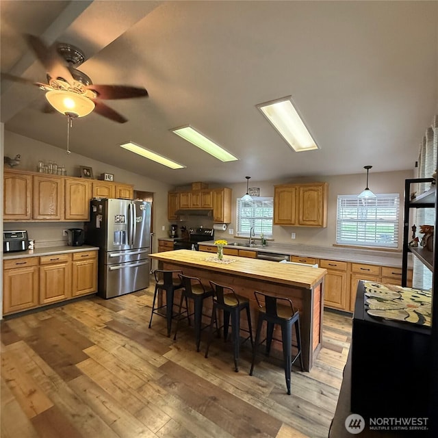 kitchen featuring range with electric cooktop, light wood-style flooring, a sink, stainless steel fridge with ice dispenser, and vaulted ceiling