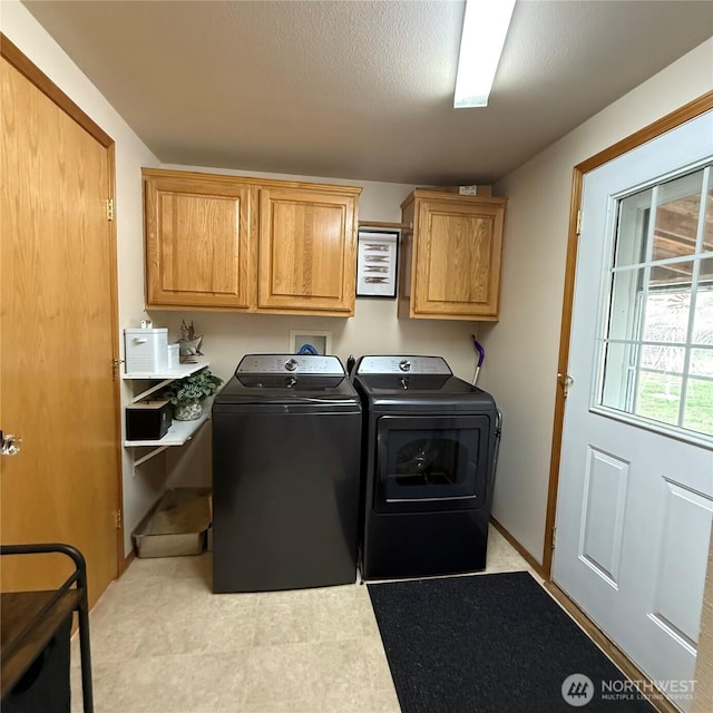 clothes washing area with cabinet space, a textured ceiling, and washer and clothes dryer