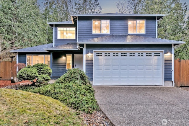 view of front of house featuring a shingled roof, concrete driveway, a garage, and fence