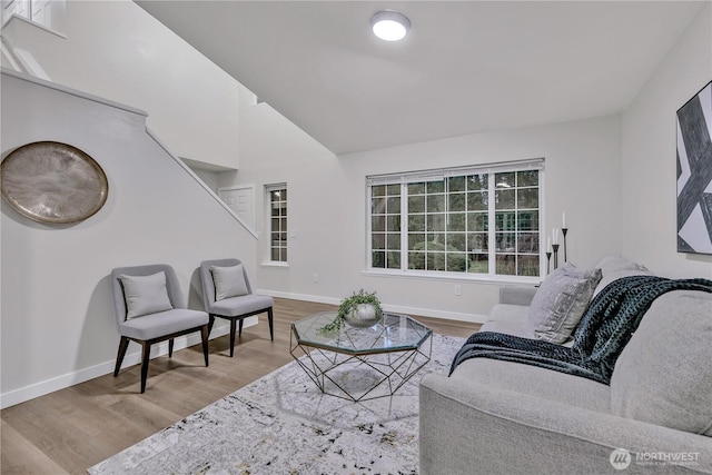 living room featuring baseboards, lofted ceiling, and wood finished floors