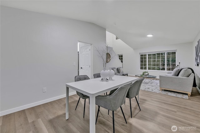 dining area with baseboards, light wood-style floors, and lofted ceiling