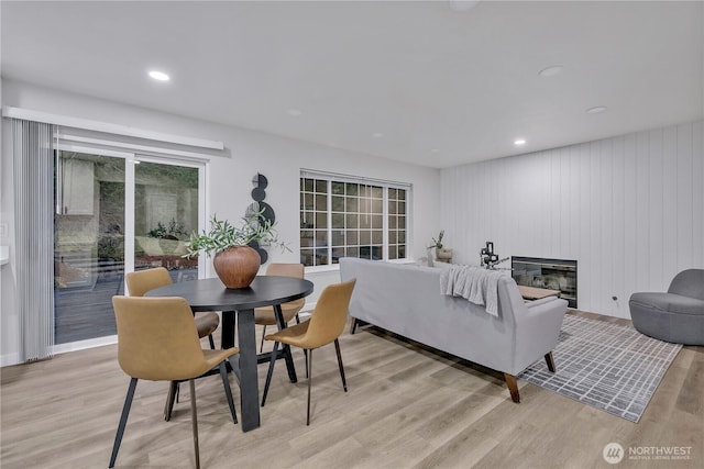 dining area with recessed lighting, a glass covered fireplace, and light wood finished floors