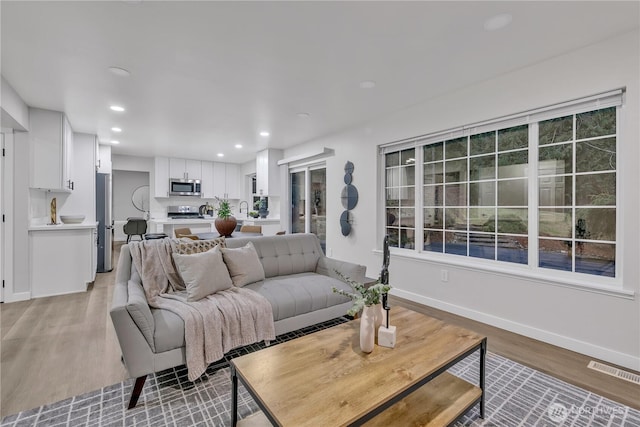 living area featuring recessed lighting, visible vents, light wood finished floors, and baseboards