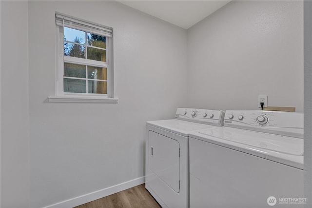 clothes washing area featuring washer and clothes dryer, laundry area, baseboards, and wood finished floors