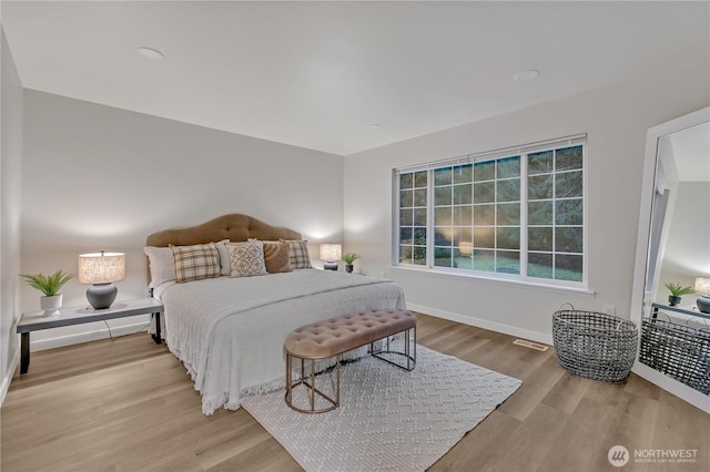 bedroom featuring visible vents, baseboards, and wood finished floors