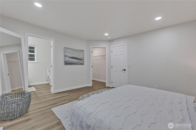 bedroom featuring recessed lighting, a walk in closet, baseboards, and wood finished floors