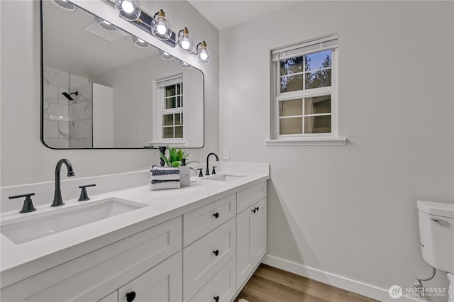 bathroom featuring toilet, wood finished floors, baseboards, and a sink