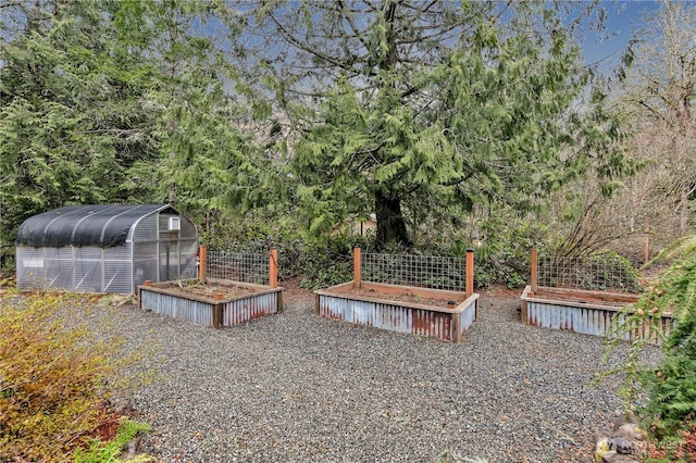 view of yard with a view of trees, a vegetable garden, and an outdoor structure