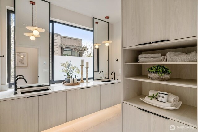 interior space featuring modern cabinets, a sink, open shelves, light countertops, and hanging light fixtures