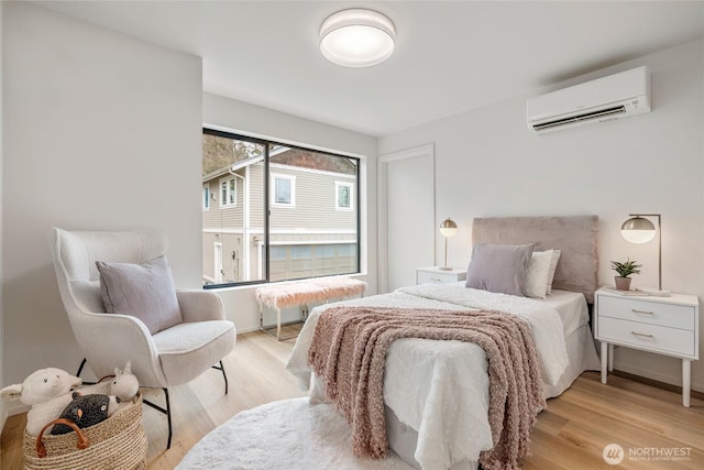 bedroom with light wood finished floors and a wall mounted AC