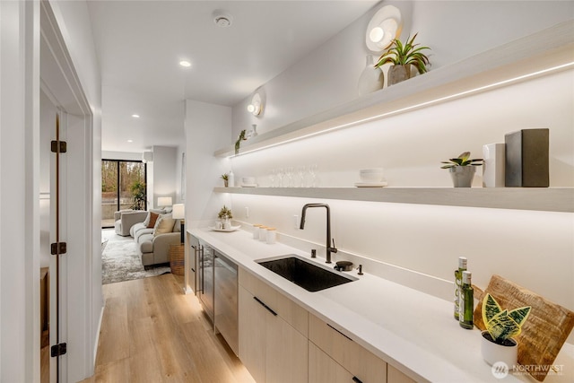 kitchen featuring light wood finished floors, open shelves, a sink, light countertops, and modern cabinets