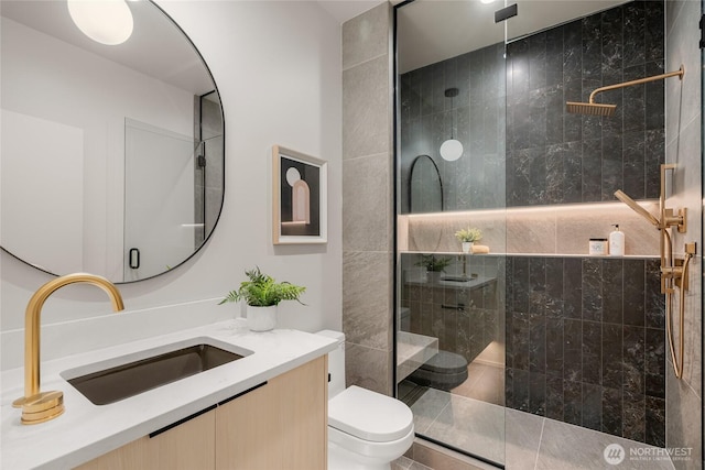 full bath featuring tiled shower, toilet, and vanity