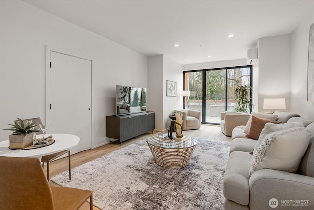 living room featuring an AC wall unit, recessed lighting, and light wood-style floors