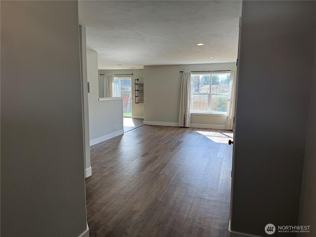 interior space with dark wood-style floors, baseboards, and a healthy amount of sunlight