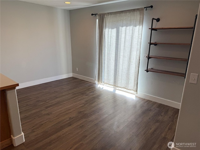 empty room with dark wood-style floors and baseboards