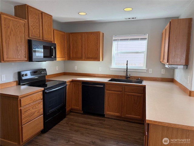 kitchen featuring visible vents, dark wood finished floors, light countertops, black appliances, and a sink