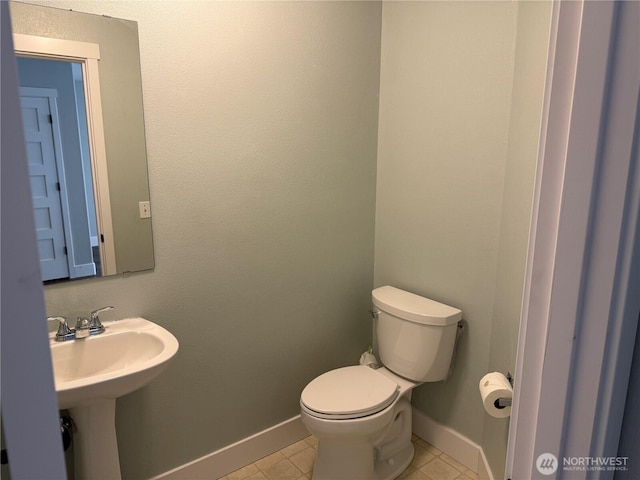 bathroom featuring tile patterned flooring, toilet, baseboards, and a sink