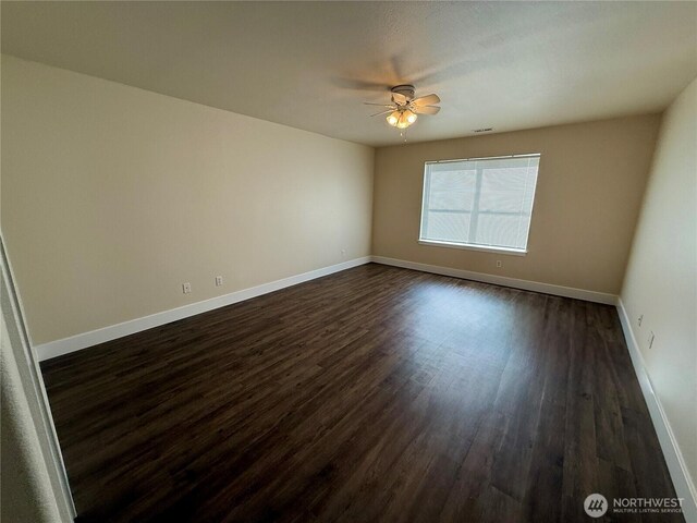 empty room with visible vents, baseboards, dark wood-style flooring, and a ceiling fan