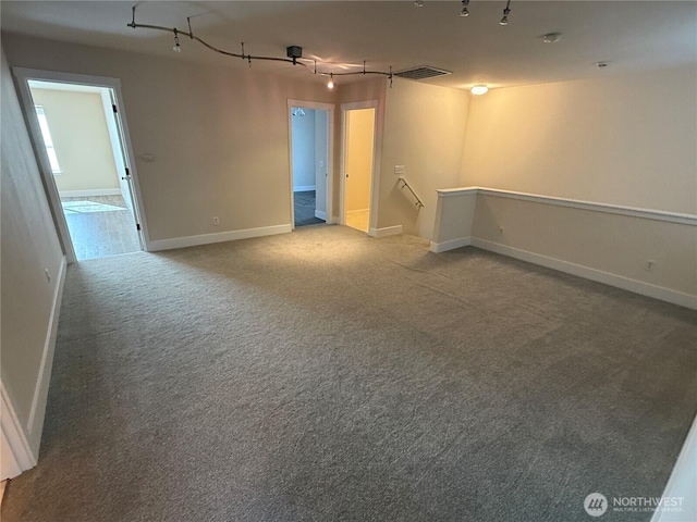 carpeted empty room featuring visible vents, baseboards, and track lighting