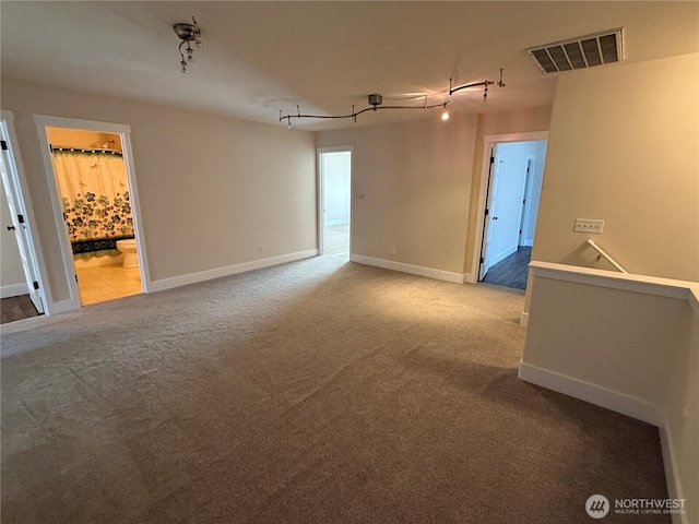 spare room with rail lighting, visible vents, baseboards, and carpet flooring