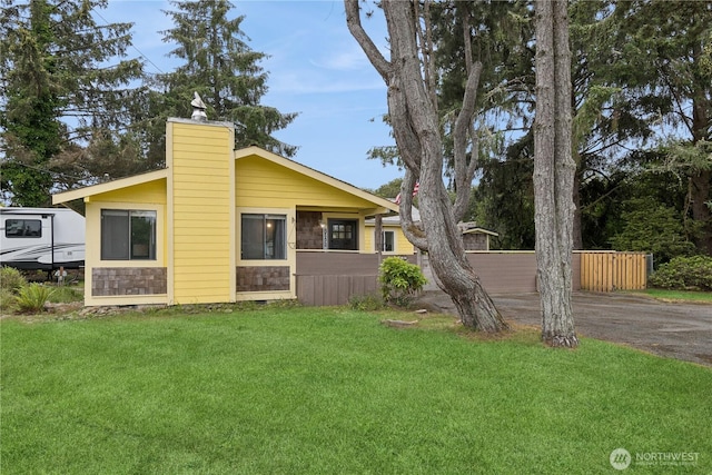 view of front of house featuring a front lawn, fence, and a chimney