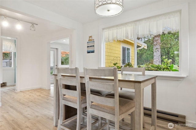 dining area with light wood finished floors, rail lighting, and baseboards