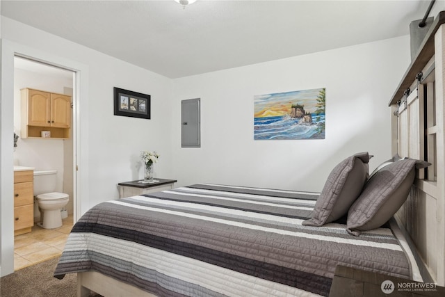 bedroom with electric panel, light tile patterned floors, and connected bathroom