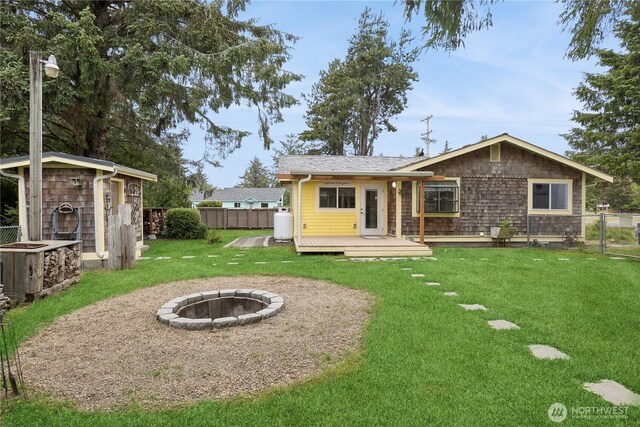 back of property featuring an outbuilding, a deck, a yard, and fence