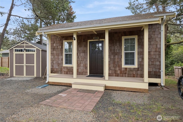 view of exterior entry with a porch and a shingled roof