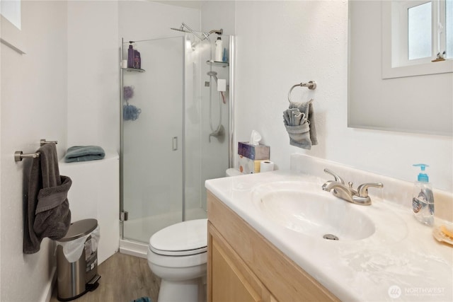 full bath featuring vanity, a shower stall, toilet, and wood finished floors