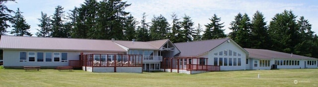 rear view of property with a lawn, a wooden deck, and a sunroom