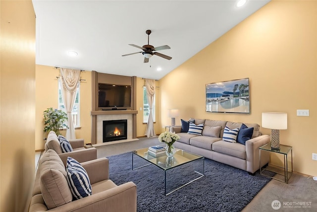 carpeted living room with a fireplace with flush hearth, a healthy amount of sunlight, a ceiling fan, and vaulted ceiling