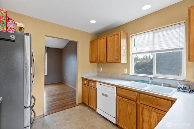 kitchen featuring a sink, freestanding refrigerator, recessed lighting, light countertops, and dishwasher