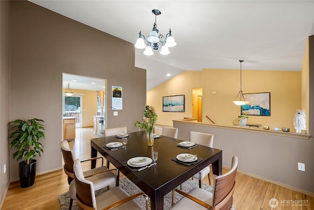 dining space with light wood finished floors, baseboards, an inviting chandelier, and vaulted ceiling