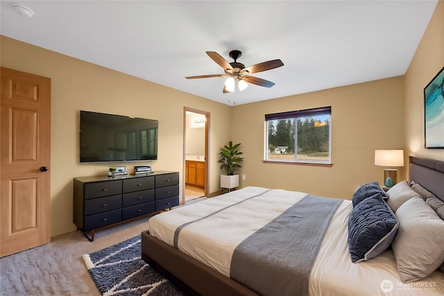 bedroom featuring light carpet, ensuite bath, and a ceiling fan