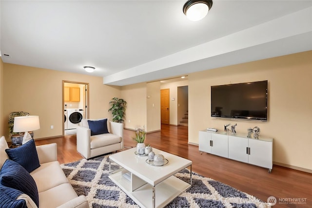 living room featuring stairs, wood finished floors, baseboards, and washer and clothes dryer