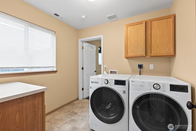 washroom with washer and dryer, visible vents, cabinet space, and baseboards