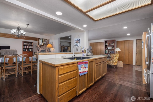 kitchen with light countertops, open floor plan, dark wood-style flooring, and a sink